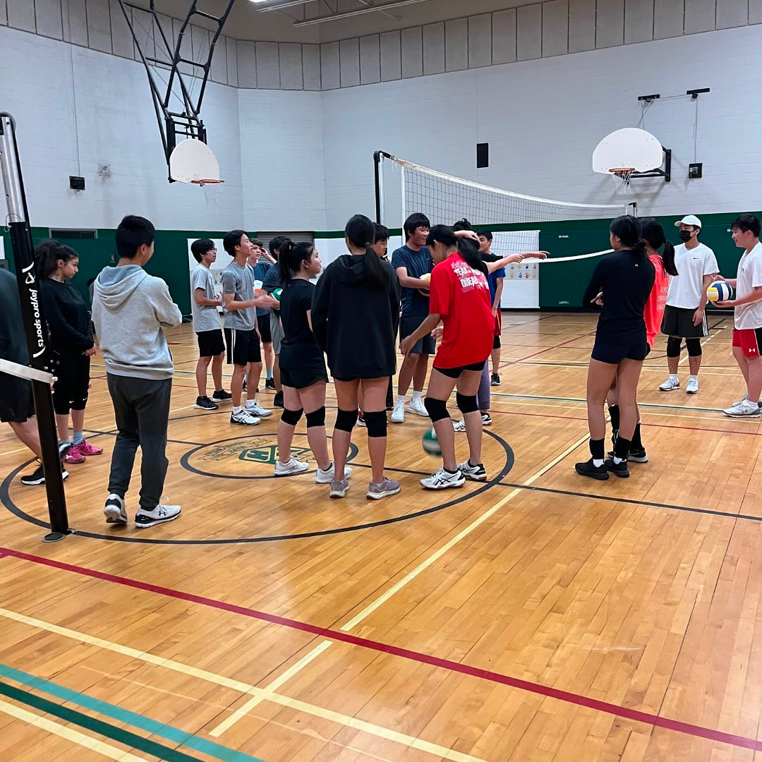 Students gathered on a volleyball court during a Scuola sports session.
